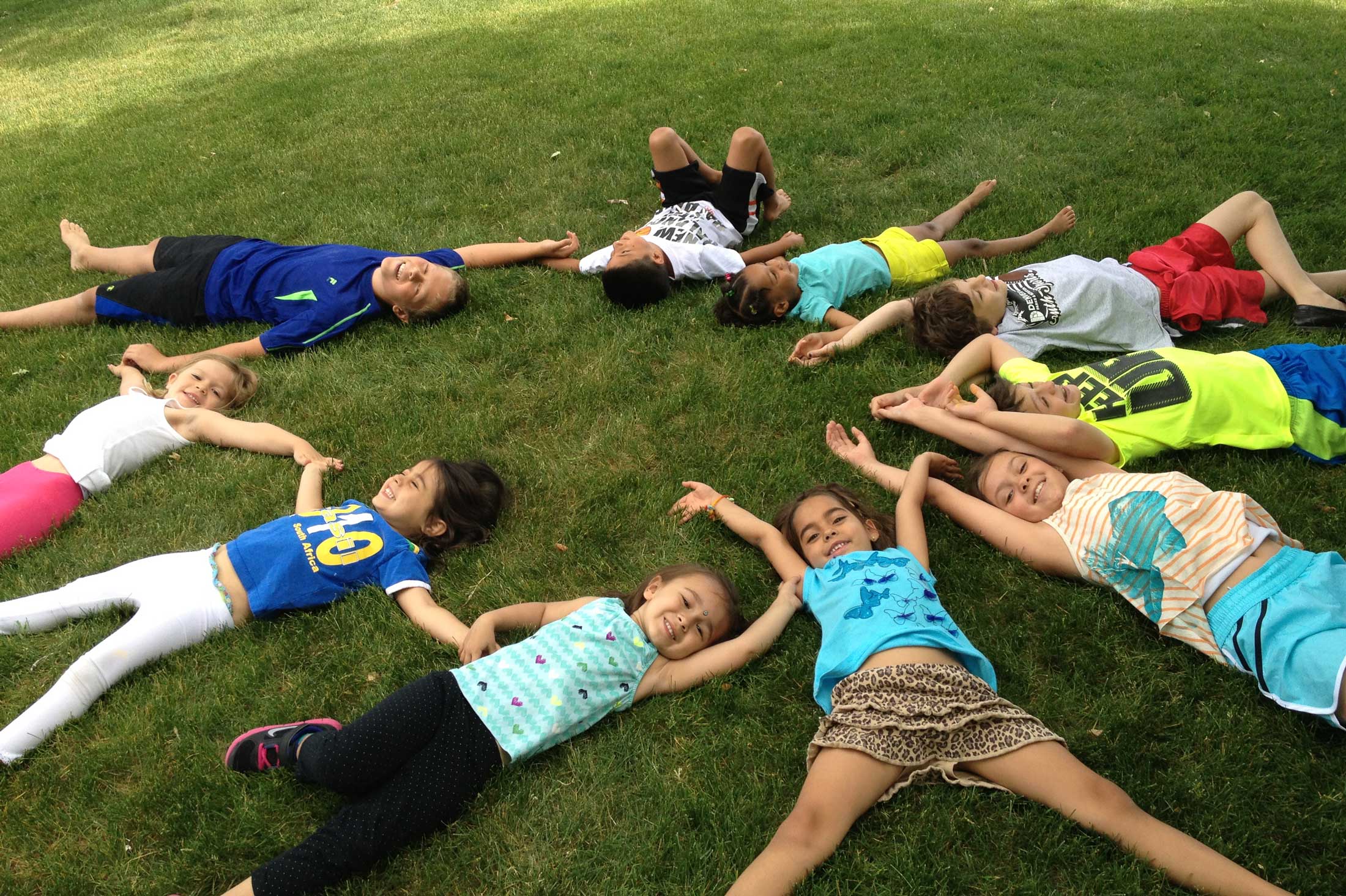 Kids lying in a circle on the grass